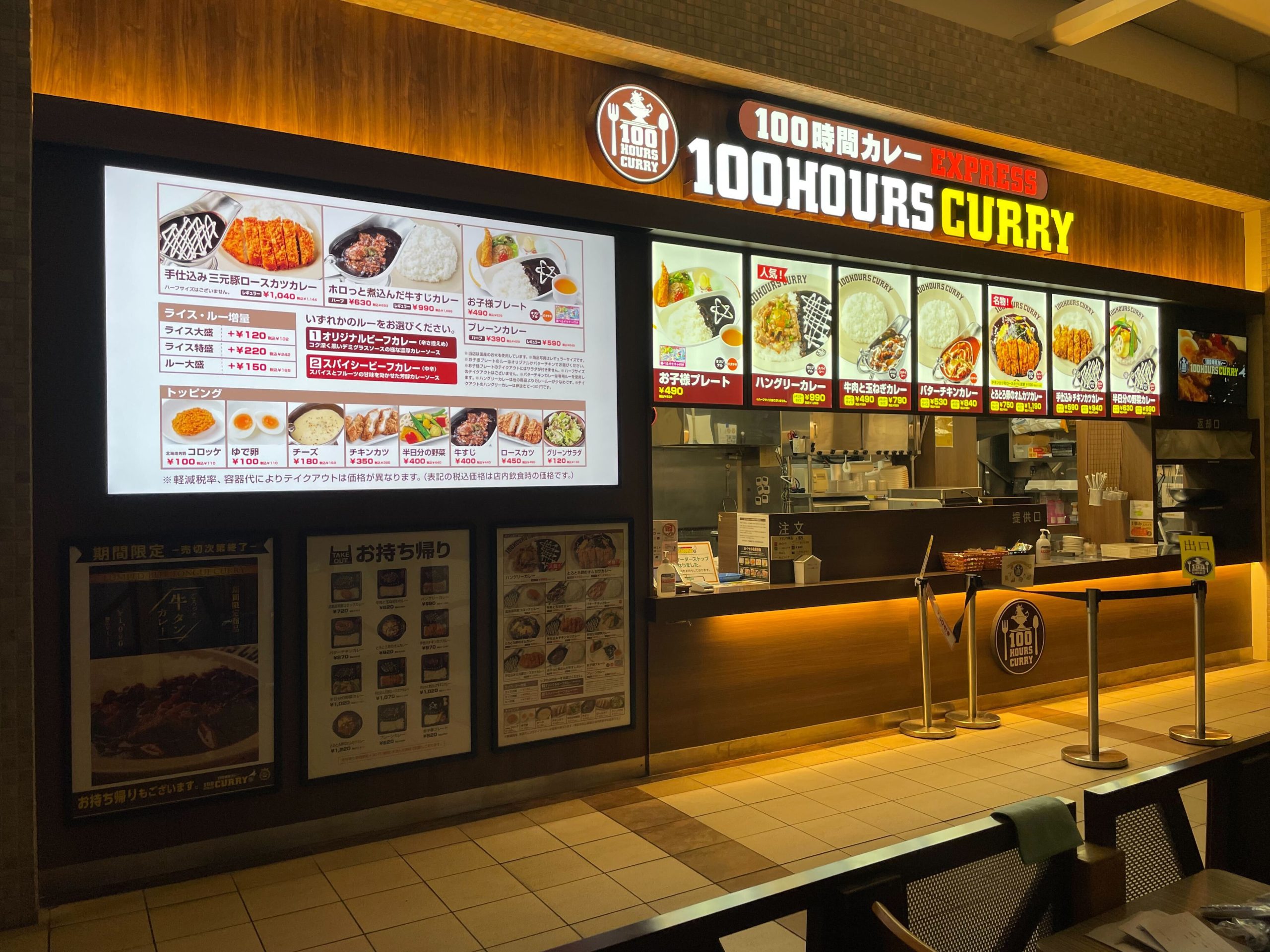 100時間カレー EXPRESS 店舗に設置されたデジタルサイネージ。お持ち帰りメニューや限定商品を明るく表示し、視認性を高めている。